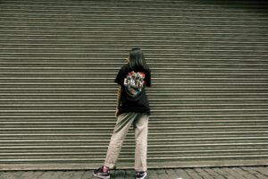 Woman standing in front of a metal shutter wearing casual streetwear.