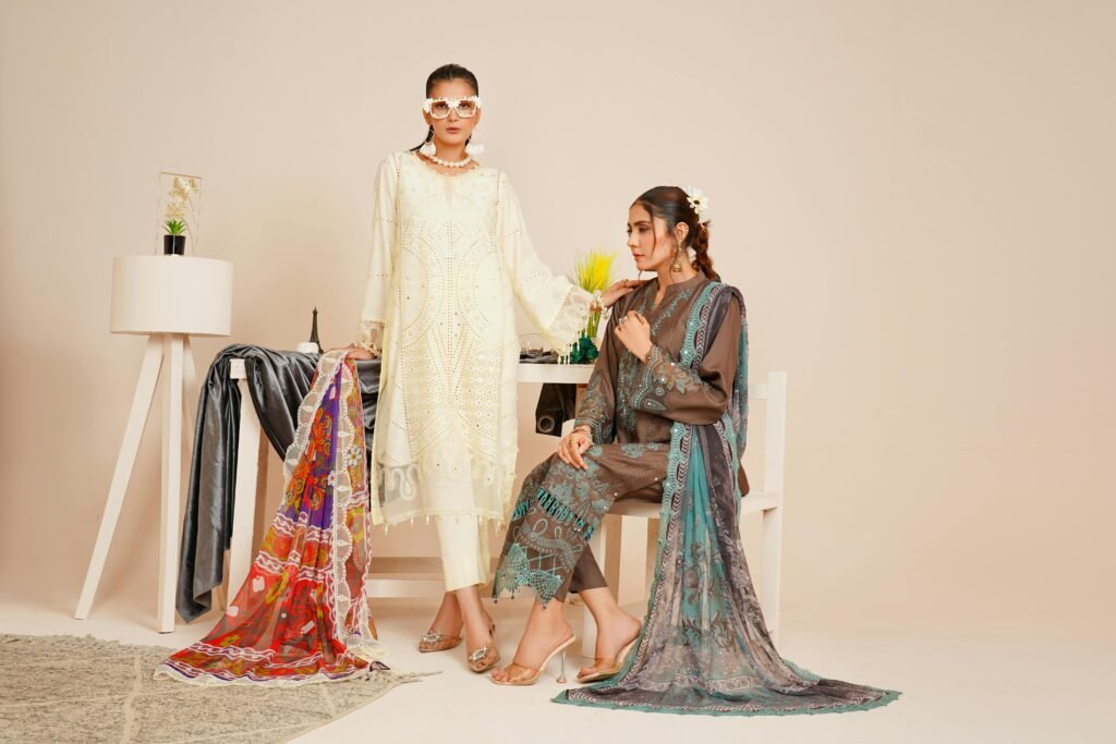 Two models in stylish Pakistani fashion attire captured in a studio setting.