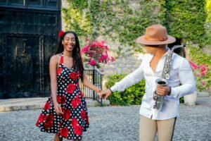 A smiling couple enjoying a moment together with a saxophone outdoors.